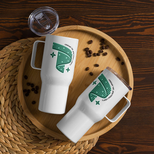 On a round wooden tray, two "Chasing the Northern Lights" travel mugs with handles, featuring white exteriors and green abstract designs along with spill-proof lids, are surrounded by scattered coffee beans on a woven mat.