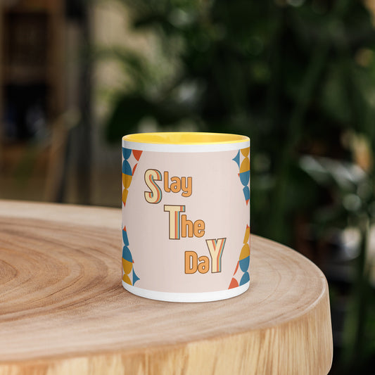 A yellow ceramic mug, named the "Slay the Day Mug," with "Slay The Day" inscribed on it and adorned with a geometric pattern, rests on a wooden table. It is both dishwasher and microwave safe for ultimate convenience.